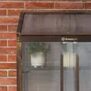 A close-up view of a mini greenhouse with plants inside, set against a brick wall. Voir les images du produit