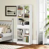 A white bookshelf filled with books and decorative items is placed next to a bed in a room. Náhľad obrázku produktu