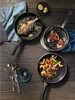 A top-down view of three WMF PermaDur Premium frying pans on a wooden table, each containing different food items. Náhľad obrázku produktu