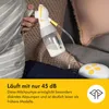 A person is using a Medela electric breast pump while sitting on a couch. Podgląd zdjęcia produktu