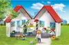 A Playmobil pet shop playset with figures and animals in a grassy outdoor setting with buildings in the background. Produktbild-Vorschau