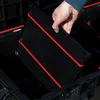 A hand is holding a black plastic tray with red accents over an open black storage container. Náhled obrázku produktu