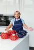 A woman in an apron stands in a modern kitchen with several polka-dot pots on the counter. Anteprima dell’immagine prodotto