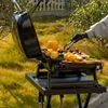 A person is grilling food on a portable gas grill outdoors. Produktbild-Vorschau