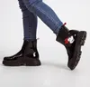A person wearing blue jeans and black boots. Produktbild-Vorschau