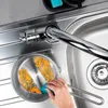 A hand is cleaning a small pot in a kitchen sink with a sponge. Produktbild-Vorschau