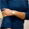 A close-up shot of a woman's arm wearing a watch and a ring, with her other arm crossed over it. Produktbild-Vorschau