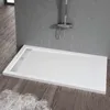 A white shower tray with a chrome shower fixture above it, set against a grey wall and wooden floor. Produktbild-Vorschau