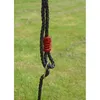 A close-up of a black rope with a red plastic component and a metal ring, likely part of a swing set or playground equipment, against a blurred green and light gray background of grass and possibly sky. Produktbild-Vorschau