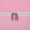 A close-up view of two zippers on a pink, plush fabric. Produktbild-Vorschau