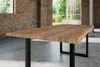 A wooden dining table with a live edge and black metal legs, set in a room with exposed brick walls and large windows overlooking a garden. Produktbild-Vorschau