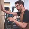 A man is using a Bosch cordless impact wrench to drill into a wooden surface. Voir les images du produit