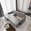A grey sectional sofa with storage compartments open, shown in a well-lit room with sheer curtains and marble flooring. Produktbild-Vorschau