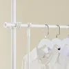 A close-up view of a white telescopic clothes rack with white hangers and shirts hanging on it. Produktbild-Vorschau