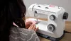 A person sewing on a white sewing machine. Produktbild-Vorschau