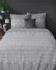 A bed with gray bedding featuring a white fan pattern. Produktbild-Vorschau