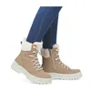 A pair of beige lace-up boots with white fur trim, worn by a person in blue jeans. Voir les images du produit