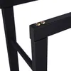 A close-up view of the black metal frame of a firewood rack, showing the connection point with two gold-colored screws. Produktbild-Vorschau