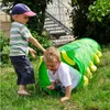 Two young children playing with a caterpillar-shaped tunnel in a grassy outdoor area. Produktbild-Vorschau