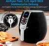An air fryer is shown on a wooden table with cut potatoes and condiments in bowls. Produktbild-Vorschau