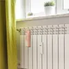 A pink ceramic pig-shaped humidifier is attached to a white radiator next to a yellow curtain. Produktbild-Vorschau