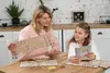 A mother and daughter are assembling a wooden puzzle on a table. Podgląd zdjęcia produktu