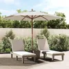 Two lounge chairs and a large umbrella are set up on a patio, surrounded by lush greenery and a wooden fence. Anteprima dell’immagine prodotto