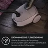 A vacuum cleaner is shown on a wooden floor with a foot pressing down on it, indicating foot operation. A text overlay describes its features. Produktbild-Vorschau