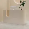 A modern reception desk with a computer and a plant. Produktbild-Vorschau