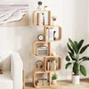 A S-shaped bookshelf filled with books and decorative items, placed next to a sofa and a large potted plant in a living room setting. Podgląd zdjęcia produktu