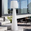 A large white floor lamp is placed on a stone staircase outside a modern building with large windows. Produktbild-Vorschau