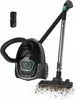 A black vacuum cleaner with its accessories and a pile of dirt being vacuumed. Produktbild-Vorschau