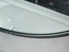 A close-up view of the edge of a round mirror with a black frame, resting on a textured surface. Anteprima dell’immagine prodotto