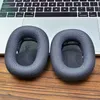 Two ear pads for headphones are placed on a wooden surface in front of a laptop keyboard. Produktbild-Vorschau