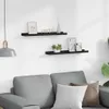 Two black shelves mounted on a white wall above a gray sofa. Voir les images du produit