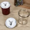 A jar of jam with a lid featuring a deer illustration, and an empty jar next to it, on a wooden surface. Voir les images du produit