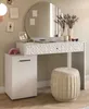A white vanity table with a round mirror, a stool, and a side cabinet, decorated with framed pictures and a vase of dried flowers. Produktbild-Vorschau
