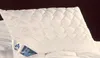 A white quilted pillow with a label attached. Produktbild-Vorschau