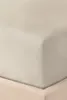 A close-up view of a beige fitted sheet and a bed skirt. Produktbild-Vorschau