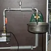A close-up view of a plumbing system with a pump, pipes, and a bowl. Náhľad obrázku produktu