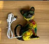 A colorful cat-shaped lamp with a USB cable and switch is placed on a wooden surface. Produktbild-Vorschau