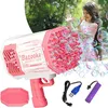 Pink-weiße Bazooka-Blasenpistole mit Blasenlösungsschale, USB-Kabel und Batterie, neben einem Kind, das draußen mit Blasen spielt Náhled obrázku produktu