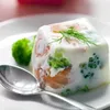 A close-up of a food mold containing salmon and broccoli, served on a white plate with a spoon and a sprig of dill on top. Podgląd zdjęcia produktu