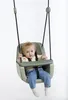 A baby sitting in a green swing seat. Podgląd zdjęcia produktu
