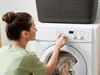 A woman is operating a washing machine. Produktbild-Vorschau
