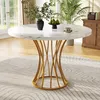 A round marble-top dining table with a gold pedestal base is set in a well-lit dining room with plants and a wooden cabinet in the background.