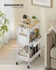 A white rolling cart with a wooden top is shown in a room with a couch and curtains. Produktbild-Vorschau