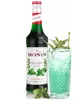 A bottle of Monin Green Mint syrup next to a glass of a mint-colored drink with ice and a straw. Podgląd zdjęcia produktu