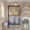 A laundry room with a rolling garment rack filled with clothes and a washing machine. Voir les images du produit