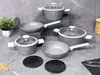 A set of cookware arranged on a textured gray surface, with a plant and a jar of pasta in the background. Podgląd zdjęcia produktu